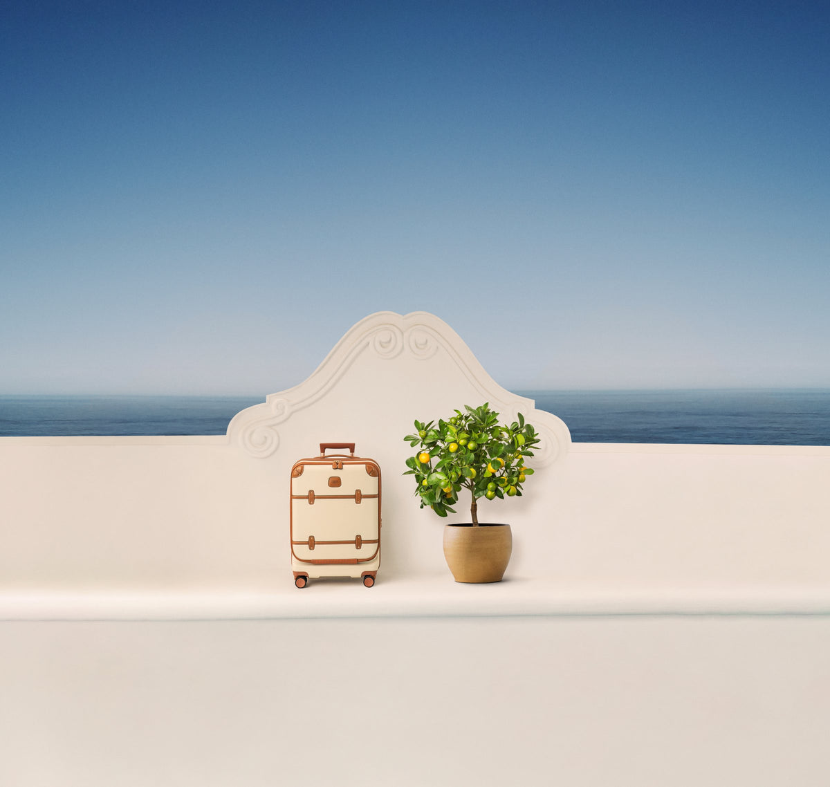 Cream Bric's Bellagio carry-on beside a lemon tree on a terrace above the sea