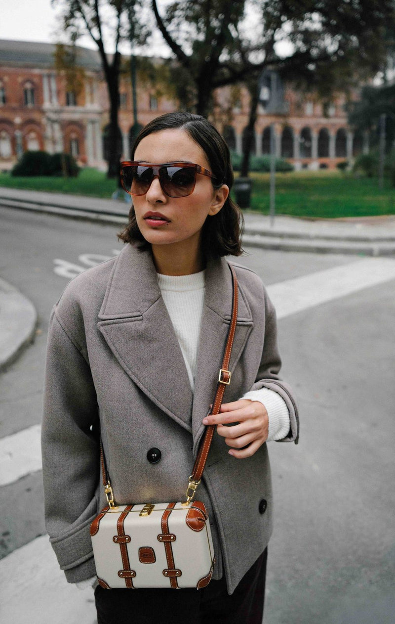 Woman in a gray coat wearing a cream Bric's Bellagio Legacy mini crossbody bag across the body