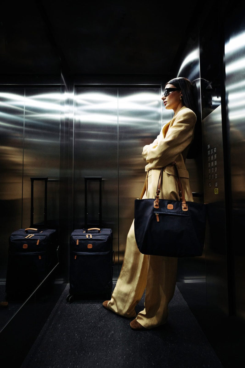 Woman in a lift carrying a navy Bric's X-Collection Sportina bag on her shoulder